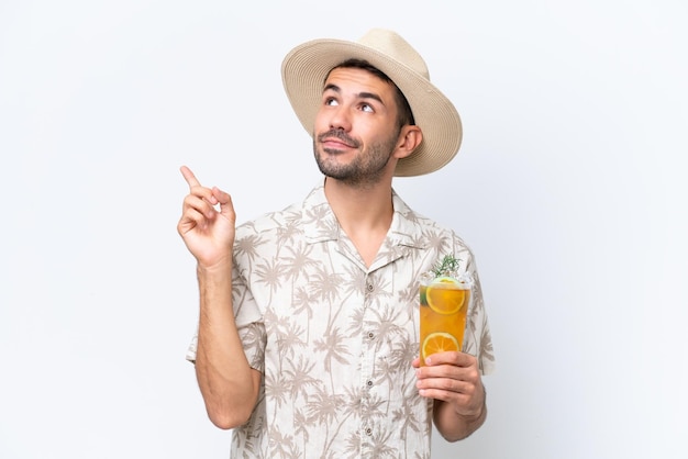 Young caucasian man holding a cocktail isolated on white background pointing up a great idea