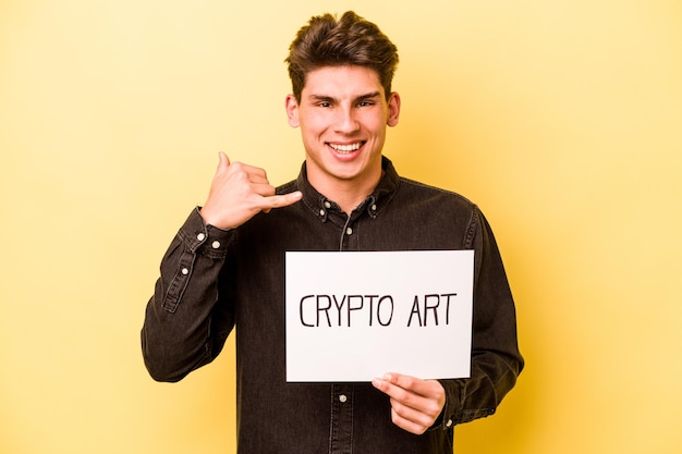 Young caucasian man holding crypto art placard isolated on yellow background showing a mobile phone call gesture with fingers
