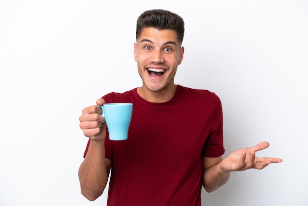 Young caucasian man holding cup of coffee isolated on white background with shocked facial expression