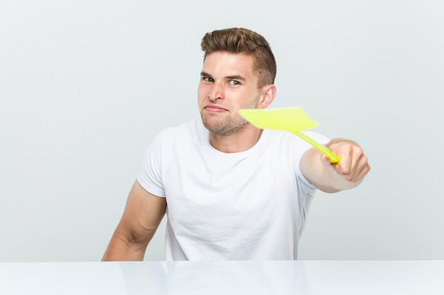 Young caucasian man holding a fly swatter