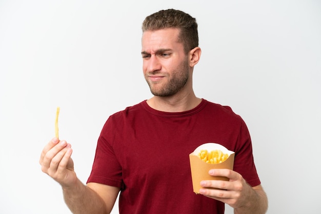 Young caucasian man holding fries potatoes isolated on white background