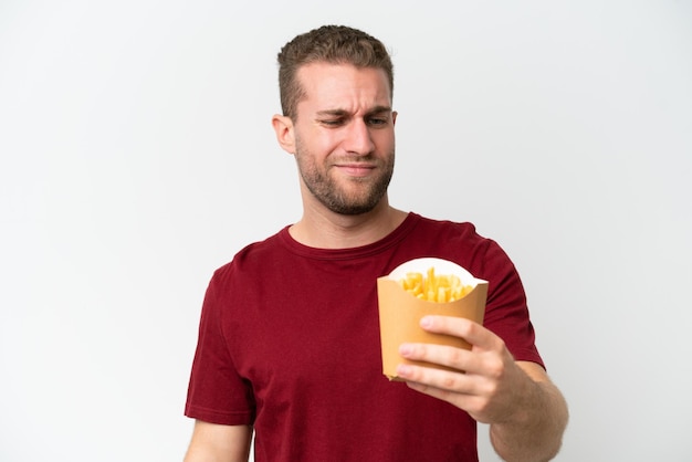 Young caucasian man holding fries potatoes isolated on white background