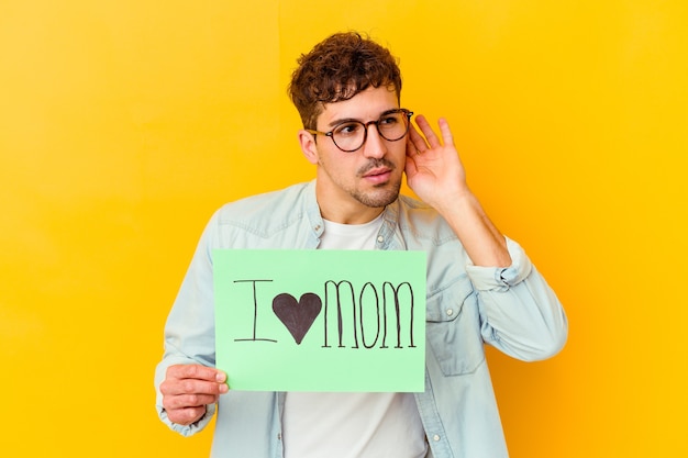 Young caucasian man holding a i love mom placard