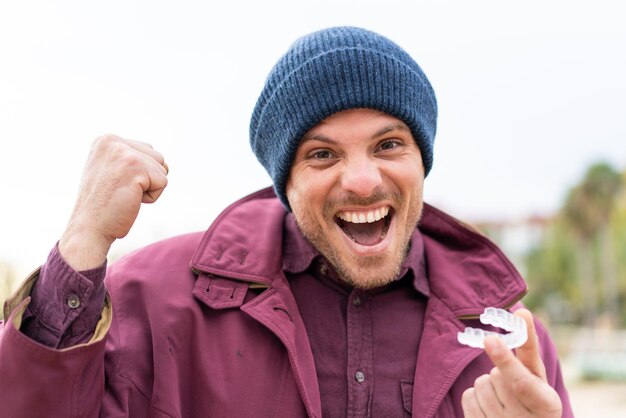 Young caucasian man holding invisible braces at outdoors