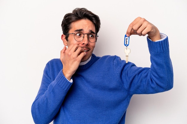 Young caucasian man holding a key chain isolated on white background