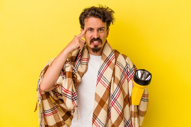 Young caucasian man holding lantern isolated on yellow background showing a disappointment gesture with forefinger