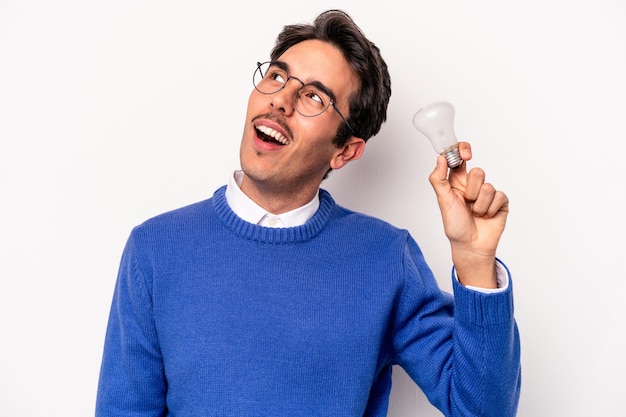 Young caucasian man holding a lightbulb isolated on white background