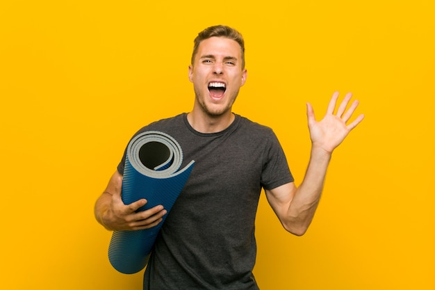 Young caucasian man holding a mat celebrating a victory or success