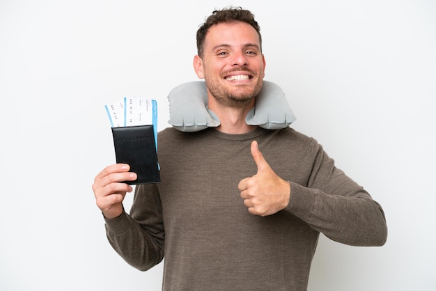 Young caucasian man holding a passport isolated on white background giving a thumbs up gesture