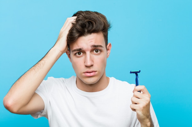 Young caucasian man holding a razor blade being shocked, she has remembered important meeting.