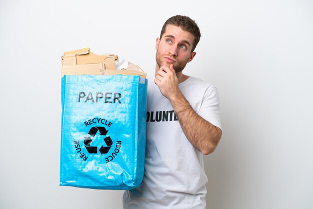 Young caucasian man holding a recycling bag full of paper to recycle isolated on white background and looking up