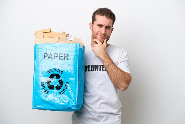 Young caucasian man holding a recycling bag full of paper to recycle isolated on white background thinking