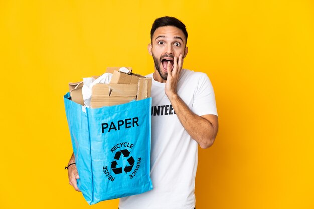 Young caucasian man holding a recycling bag full of paper to recycle isolated