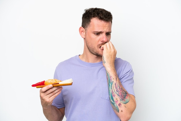 Photo young caucasian man holding sashimi isolated on white background having doubts