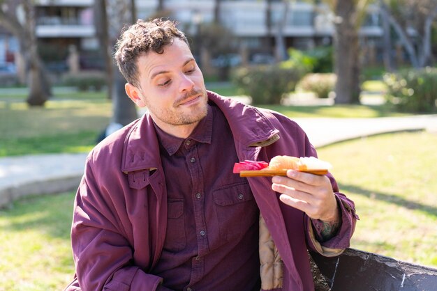 Young caucasian man holding sashimi at outdoors with sad expression