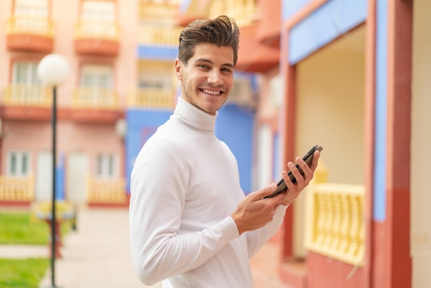 たくさんの笑みを浮かべて屋外でタブレットを保持している若い白人男性