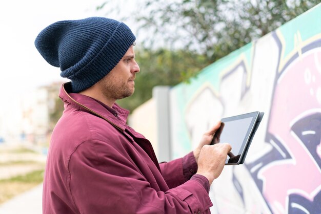 young caucasian man holding a tablet at outdoors
