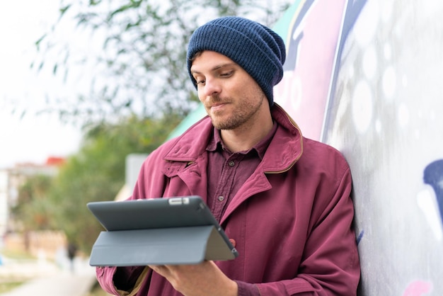 Young caucasian man holding a tablet at outdoors