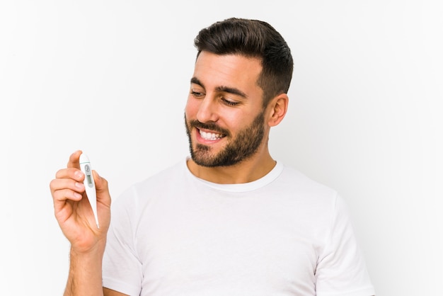 Young caucasian man holding a thermometer isolated Young caucasian man holding  a smiling confident with crossed arms.