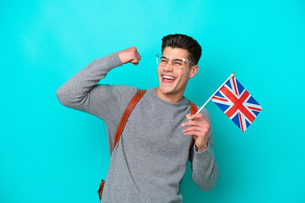 승리를 축하하는 파란색 배경에 고립 된 영국 국기를 들고 젊은 백인 남자