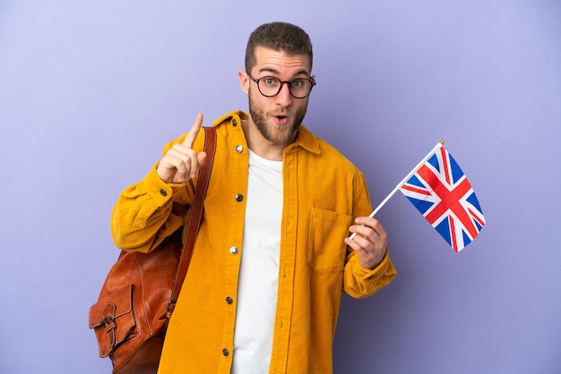 보라색에 고립 된 영국 국기를 들고 젊은 백인 남자는 손가락을 들어 올리는 동안 솔루션을 실현하려는 의도