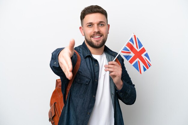 Young caucasian man holding an United Kingdom flag isolated on white background shaking hands for closing a good deal