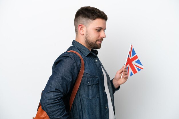 Young caucasian man holding an United Kingdom flag isolated on white background suffering from backache for having made an effort