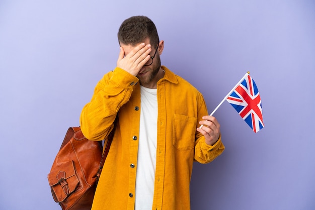 Young caucasian man holding an United Kingdom flag isolated