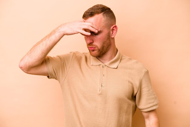 Young caucasian man isolated on beige background having a head ache touching front of the face