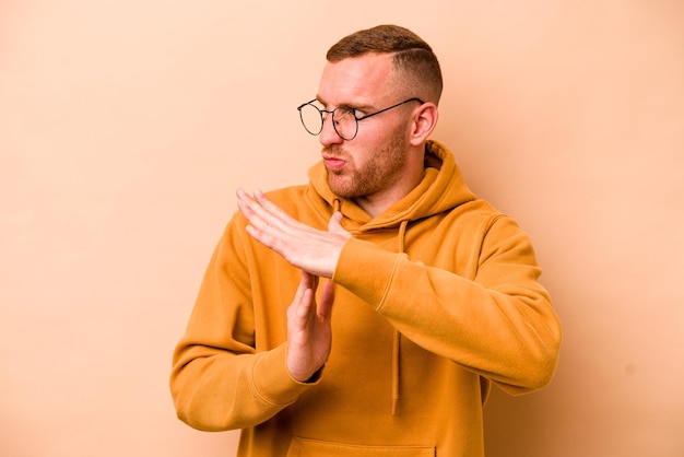 Young caucasian man isolated on beige background showing a timeout gesture