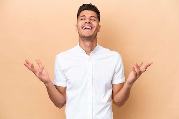 Young caucasian man isolated on beige background smiling a lot