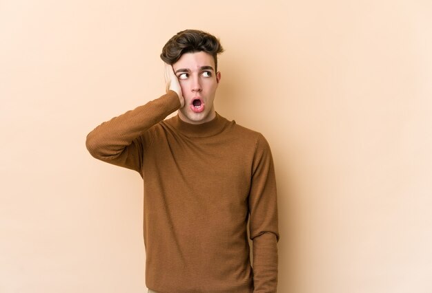 Young caucasian man isolated on beige wall being shocked, she has remembered important meeting.