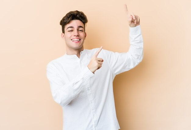 Young caucasian man isolated on beige wall dancing and having fun.