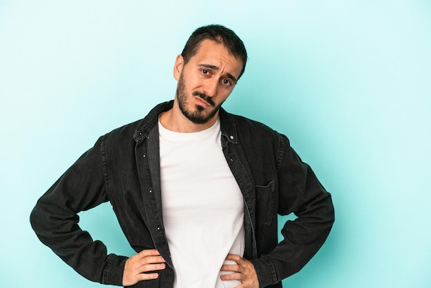 Young caucasian man isolated on blue background confused feels doubtful and unsure