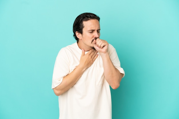 Young caucasian man isolated on blue background coughing a lot