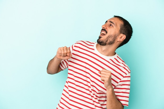 Young caucasian man isolated on blue background dancing and having fun.