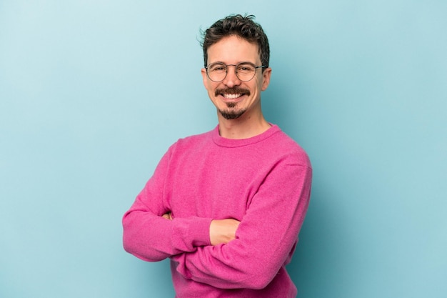 Young caucasian man isolated on blue background happy, smiling and cheerful.