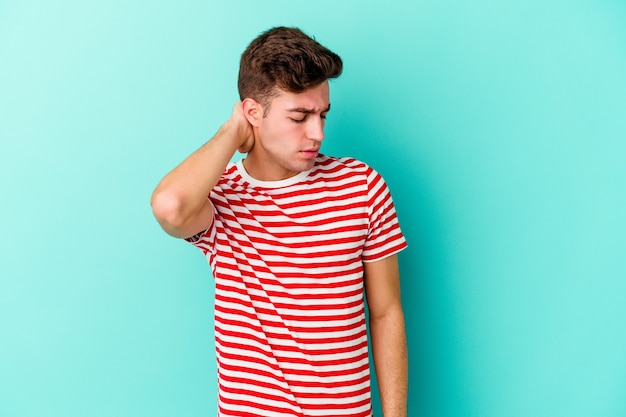Young caucasian man isolated on blue background having a neck pain due to stress, massaging and touching it with hand.