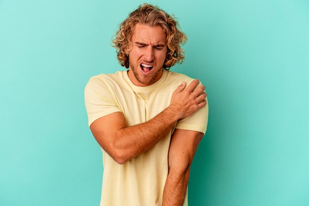 Young caucasian man isolated on blue background having a shoulder pain.