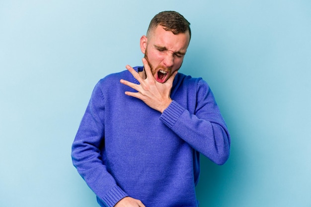 Young caucasian man isolated on blue background having a strong teeth pain molar ache