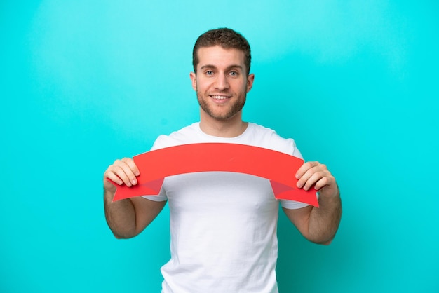 Young caucasian man isolated on blue background holding an empty placard