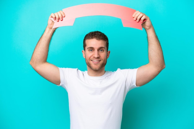 Young caucasian man isolated on blue background holding an empty placard