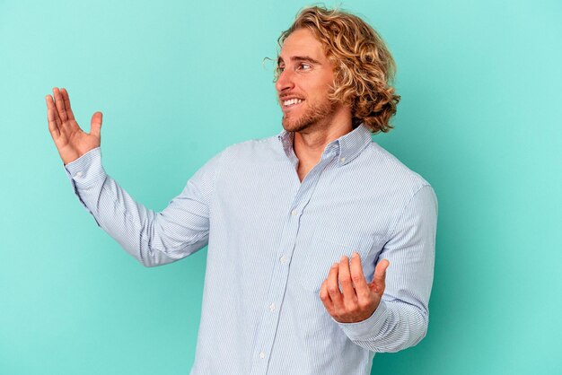 Young caucasian man isolated on blue background joyful laughing a lot. happiness concept