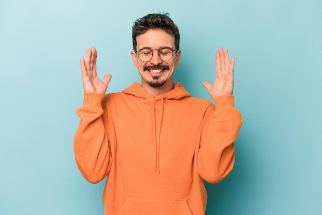 Young caucasian man isolated on blue background joyful laughing a lot. Happiness concept.