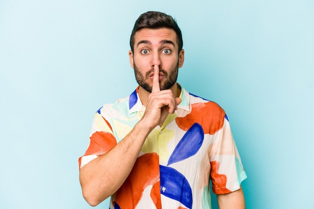 Young caucasian man isolated on blue background keeping a secret or asking for silence