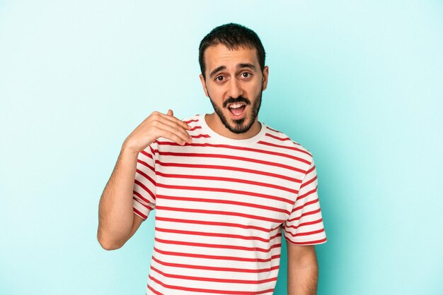 Young caucasian man isolated on blue background laughing about something covering mouth with hands