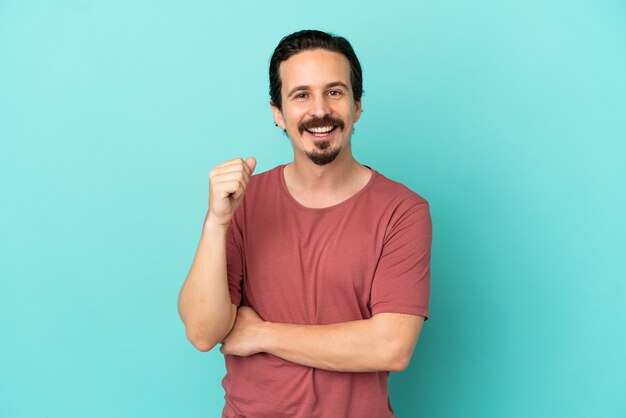 Young caucasian man isolated on blue background laughing