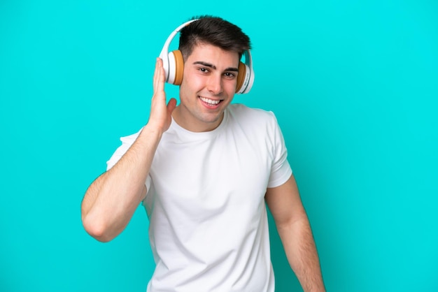 Young caucasian man isolated on blue background listening music