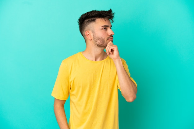 Young caucasian man isolated on blue background and looking up