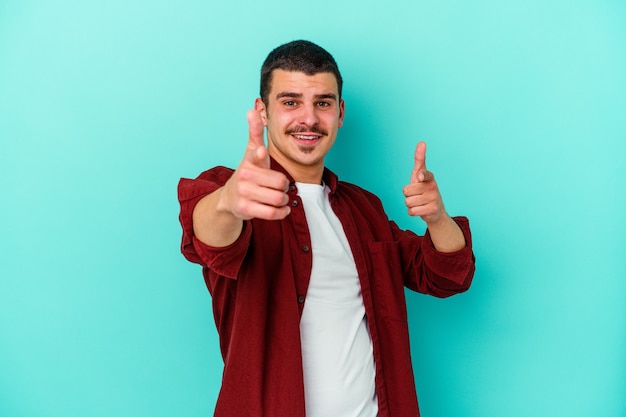 Young caucasian man isolated on blue background pointing to front with fingers.